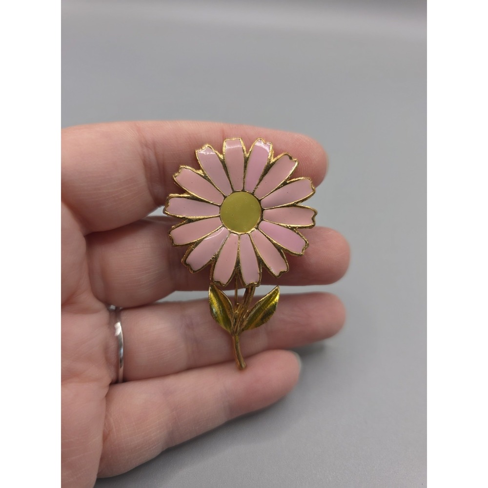 gold-tone flower brooch featuring pink enamel petals, a yellowish-green center